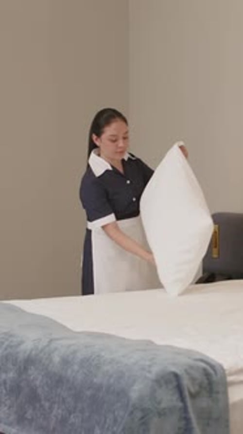 Vertical of Latin Maid Making Bed in Hotel Room