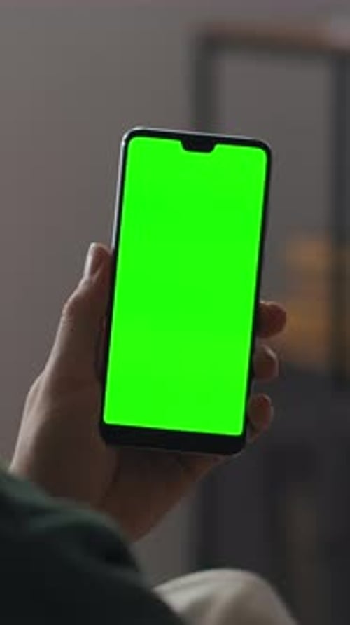 Person Holding Modern Smartphone with Bright Green Chroma Key Screen in Vertical Orientation Ready