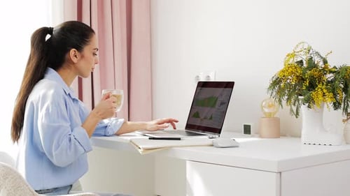 Beautiful Woman in Blue Shirt Drinking Coffee and Working on Laptop