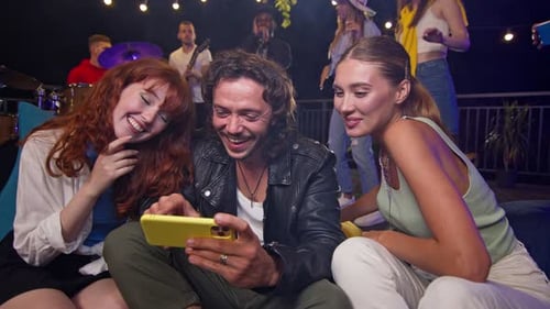 Friends Watching Phone at Rooftop Party with Band