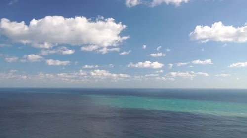 Aerial View on Azure Sea with Fluffy Cumulus Clouds Moving in Bright Sunset Sky Over Calm Sea Nature