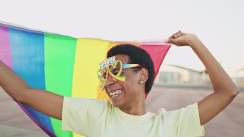 Smiling Young Adult Holding Rainbow Pride Flag
