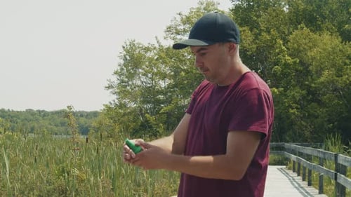 Man Applying Mosquito Repellent By the Lake on a Sunny Afternoon