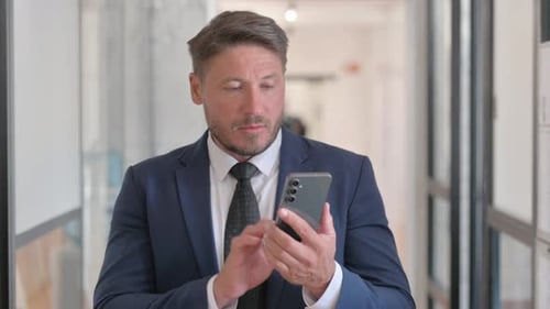 Businessman Using Smartphone in Modern Office Building
