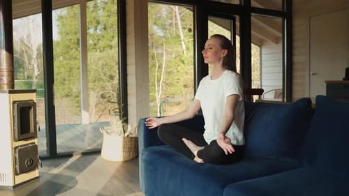 Woman Meditating Peacefully on Couch at Home