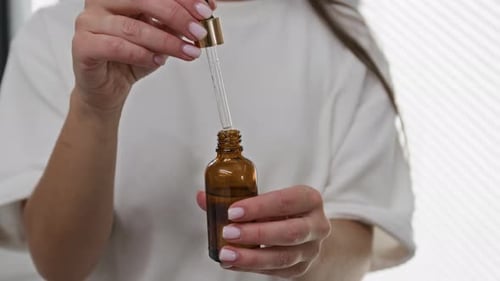 Woman Opening Bottle with Dropper, Skincare Routine