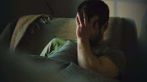 Man Lying Back With Hand Covering Face