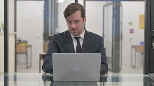 Young Adult Man Typing at Desk in Office