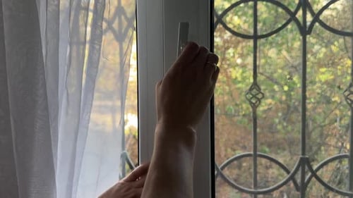 Closeup of Hands Turning a Window Handle Without Opening It Indoor Scene with Daylight and Grid