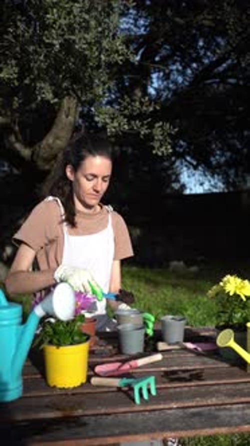 Female gardener planting flowers outdoors in a beautiful green garden