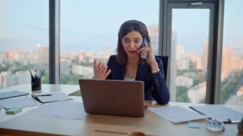 Woman working at desk using laptop and smartphone