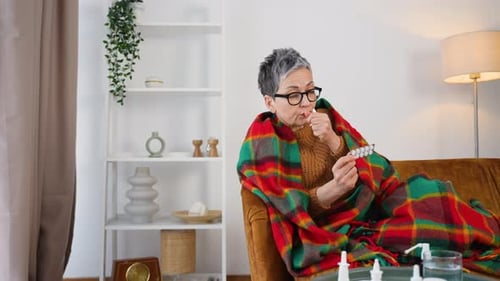 Woman Sick on Couch Taking Pill for Illness