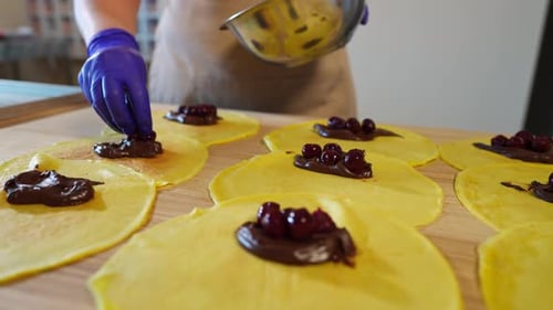 Person Making Crepes with Chocolate and Cherries