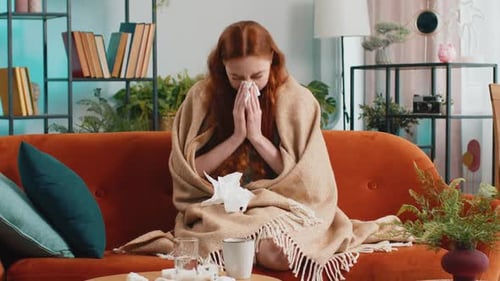 Red-haired Woman Sick on Couch Blowing Nose