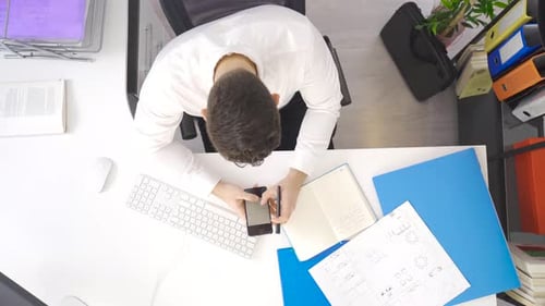 El empresario que trabaja en el proyecto mira el teléfono y los documentos.