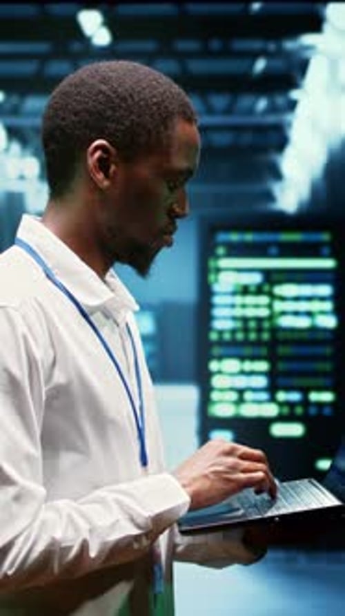 Man Typing on Laptop in Server Room