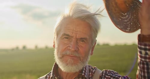 Portrait of Senior Smile Man with Beard Looking to the Camera in the Golden Field on the Blue Sky