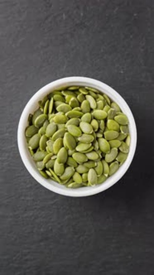 Bowl of Pumpkin Seeds on Black Stone Slate Rotating Vegetarian Nutrition