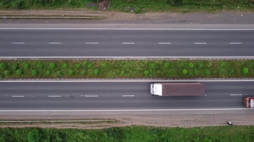 Top-down aerial view of a four-lane highway in India with pedestrians, motorcycles, passenger cars a