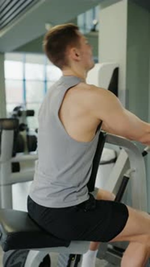 Junger Mann konzentrierte sich auf den Muskelaufbau in einem modernen Fitnessstudio