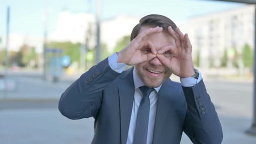 Excited Businessman Makes Glasses with Hands
