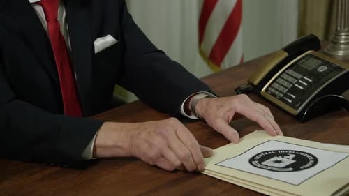 Man in Suit Looks at Files in Office