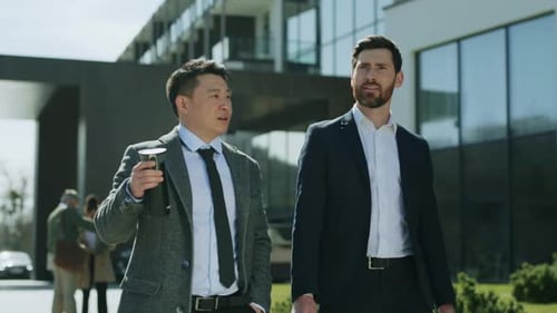 On Street Two Business Men Walking Talking Discussing in Modern City Near Business Center Hold Cup