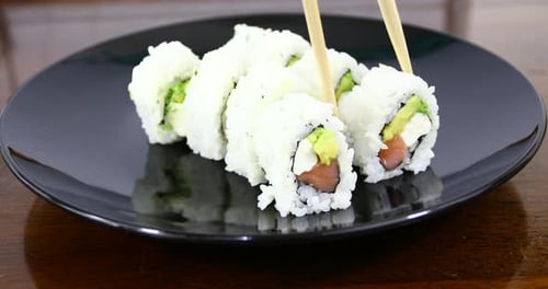 Close-Up of Sushi Roll Lifted with Chopsticks