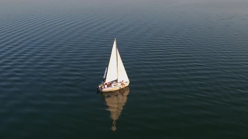Luftaufnahme einer friedlichen Flusslandschaft mit ruhigen Wellen und weißer Segelyacht — Sommerreise