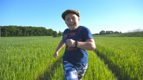 Portrait of Happy Boy is Running Through the Field with Green Wheat at a Sunny Hot Day Smiling Child