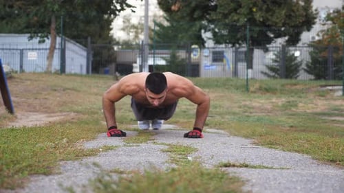 Muscular Man Doing Push-ups in Urban Park
