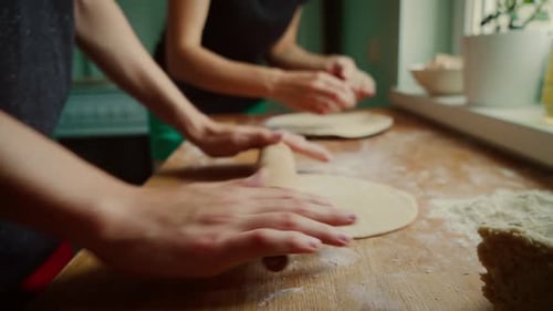 People Rolling Dough on Wooden Table in Kitchen