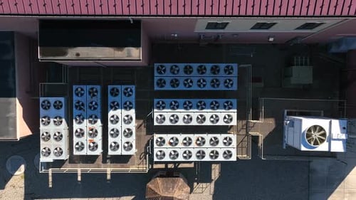 Many air condenser air conditioner units at commercial building. Descending aerial on HVAC theme. Ou