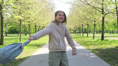 Glückliches lächelndes kleines Mädchen, das nach dem Schulunterricht ihren Rucksack dreht