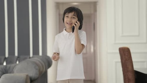 Smiling Boy Chatting on Cell Phone Indoors