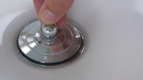 Close-up slow motion shot of plug hole hands being filled up with bubbles water sink basin bowl bath