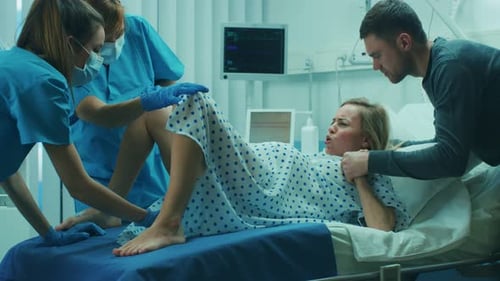 En el hospital, una mujer en trabajo de parto da a luz, los obstetras y los médicos ayudan, su esposo apoya
