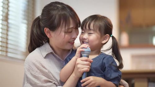 Mother and Child Singing Together with Microphone Indoors