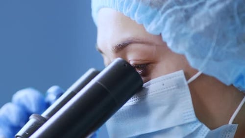 Medical Professional Analyzing Sample Through Microscope Close Up