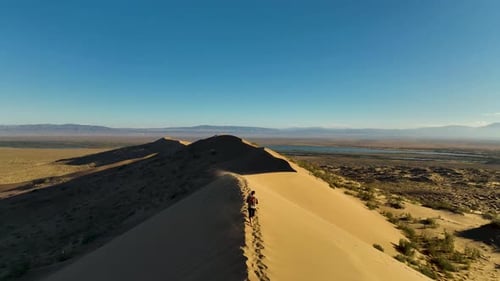 Person walking along a desert dune ridge with a panoramic landscape