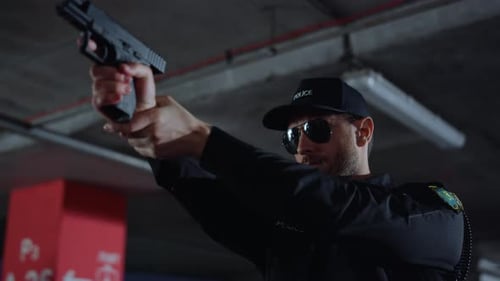 Focused police officer on duty takes aim with firearm at construction building