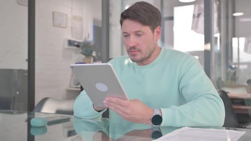 Man Surprised Using Tablet in Modern Office