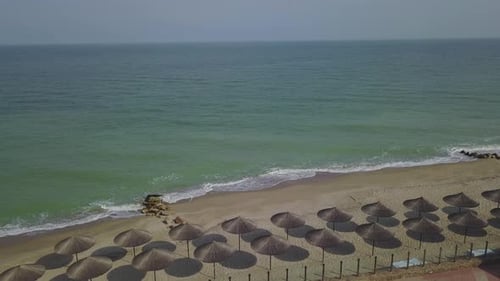 Aerial View of Straw Umbrellas on the Beach Ocean Waves Washing Sandy Shore Tranquil Coast Line of a