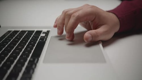 Close-up of a man's hand using a laptop trackpad for scrolling and clicking