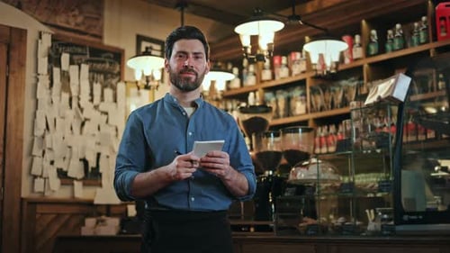 Friendly Male Waiter in Uniform Using Paper Notes While Working at Vintage Bar