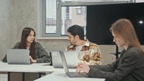 Young Adults Collaborate on Laptops in Office