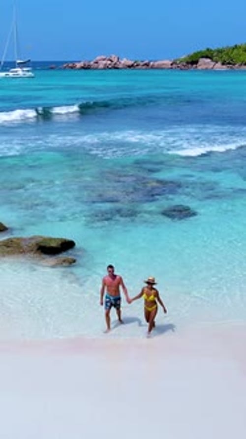 Strolling Hand in Hand Along the Pristine Shores of Seychelles Under the Bright Sun