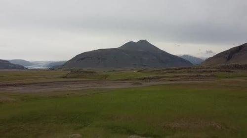 Generic landscape in Iceland with mountain in background on an overcast day, aerial dolly out