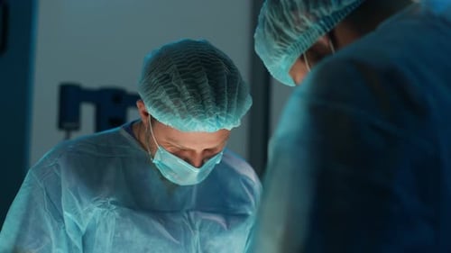 Nahaufnahme von männlichen Chirurgen und Krankenschwestern mit sterilen Handschuhen bei der Verarbeitung chirurgischer Uniformen und Masken