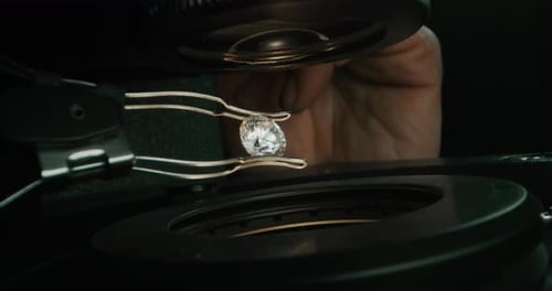 Slow motion macro close up of experienced goldsmith controlling a quality of diamond stone, select